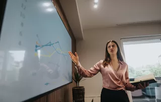 Professional businesswoman presenting growth data on a digital screen in office meeting