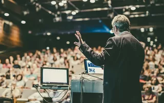 Public speaker giving talk at Business Event.